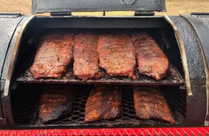 seven bbq ribs racks cooking in a smoker