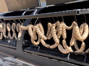 Sausage links hanging in a BBQ smoker